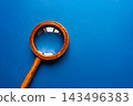 Vintage wooden magnifying glass with brass ring on vibrant blue background 143496383
