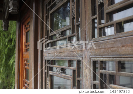 Close-up of traditional Chinese carved wooden window frame with intricate lattice patterns in an ancient garden building Close-up of traditional Chinese carved wooden window frame with intricate lattice patterns in an ancient garden building 143497853