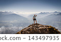 Solo male mountaineer standing on a rocky summit overlooking the Austrian Alps near Innsbruck, experiencing a moment of freedom, achievement and inspiration above the vast alpine landscape. 143497935