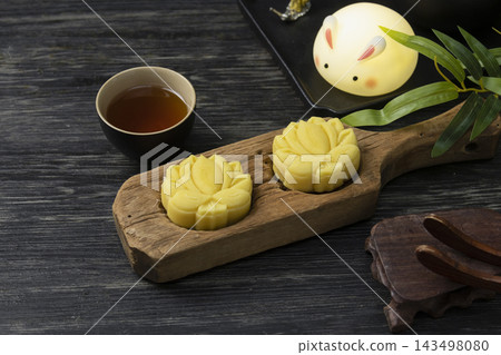Lotus-shaped mooncakes on wooden mold with Chinese tea and a rabbit lamp for Mid-Autumn Festival Lotus-shaped mooncakes on wooden mold with Chinese tea and a rabbit lamp for Mid-Autumn Festival 143498080