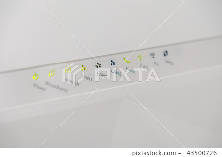 A close view of a white wireless router control panel with glowing green LED indicators, showing active internet connection status for home or office networking and data connectivity A close view of a white wireless router control panel with glowing green LED indicators, showing active internet connection status for home or office networking and data connectivity 143500726