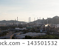 Aerial oil refinery landscape with processing towers and mountain backdrop. 143501532
