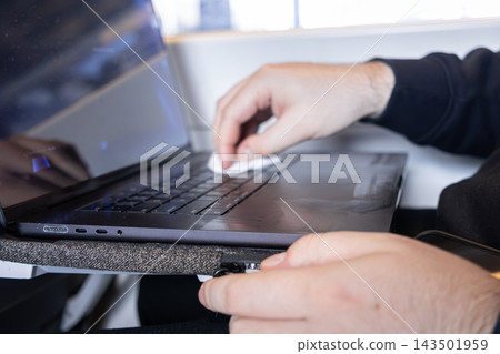 A person carefully cleans a black laptop keyboard using a soft white cloth to demonstrate essential maintenance and hygiene practices for electronic devices in a modern workspace A person carefully cleans a black laptop keyboard using a soft white cloth to demonstrate essential maintenance and hygiene practices for electronic devices in a modern workspace 143501959