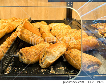 Fresh savory pastries displayed in a modern bakery showcase cabinet, inviting customers to purchase delicious golden flaky baked goods ready for breakfast or a quick afternoon snack Fresh savory pastries displayed in a modern bakery showcase cabinet, inviting customers to purchase delicious golden flaky baked goods ready for breakfast or a quick afternoon snack 143501978