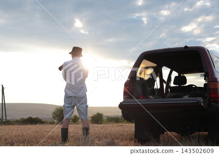 Man takes photographs in a field during sunset. 143502609