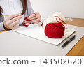 Handmade with yarn: A person knitting while taking notes on the production process. 143502620