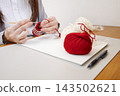 Handmade with yarn: A person knitting while taking notes on the production process. 143502621
