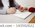 Handmade with yarn: A person knitting while taking notes on the production process. 143502622