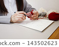 Handmade with yarn: A person knitting while taking notes on the production process. 143502623