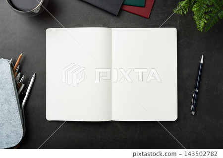 Top view of opened black hardcover notebook with pencil case and office stationery on dark stone background with copy space 143502782