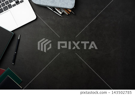 Top view of dark stone desk background with laptop, notebook and office supplies with large copy space Top view of dark stone desk background with laptop, notebook and office supplies with large copy space 143502785