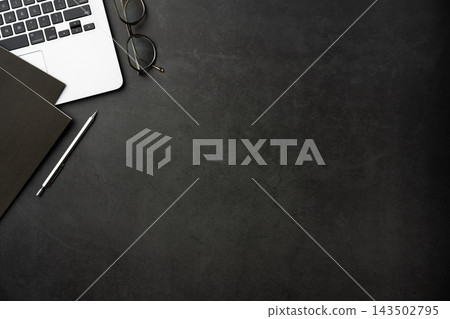Top view of dark stone desk background with laptop, notebook and office supplies with large copy space Top view of dark stone desk background with laptop, notebook and office supplies with large copy space 143502795