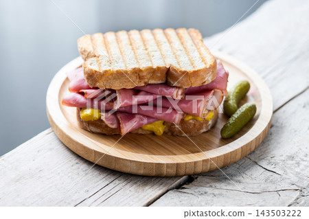 Grilled pastrami sandwich with mustard and pickles Grilled pastrami sandwich with mustard and pickles 143503222