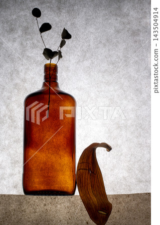 Brown bottle and plant leaf on a gray background Brown bottle and plant leaf on a gray background 143504914