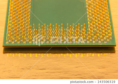 Detailed view of a computer microprocessor with multiple gold pins on a green circuit board Detailed view of a computer microprocessor with multiple gold pins on a green circuit board 143506319