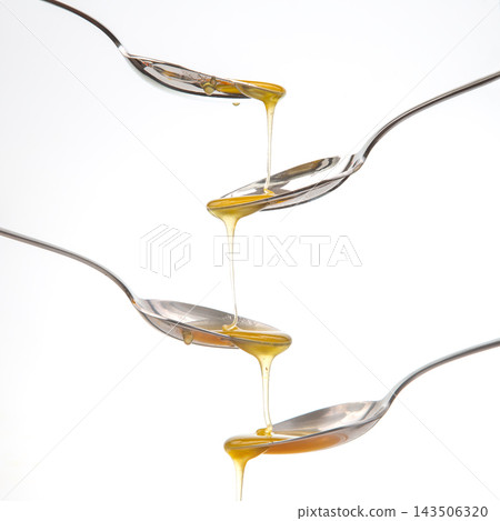 Honey flowing from one spoon to another in a creative arrangement Honey flowing from one spoon to another in a creative arrangement 143506320