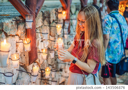 Woman holding a glowing candle during a quiet festive moment. 143506876