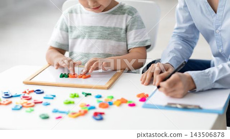 Focused Caucasian Child And Adult Playing With Colorful Letters, Engaging In Educational Activity Together At Office Desk. Exploring Language And Learning Through Hands-on Play. Educational Concept. 143506878