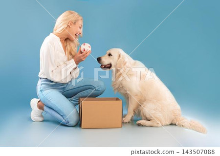 Happy Woman Smiling While Playing With Golden Retriever Dog And Ball, Enjoying Moment Together In Indoor Studio Setting. Joyful Interaction Between Pet And Owner, Love And Affection. Pet Concept. 143507088