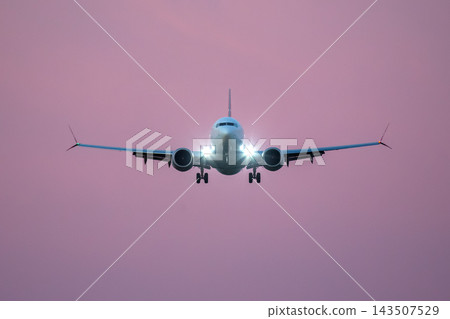 Airplane flying at dusk with pink sky in the background 143507529