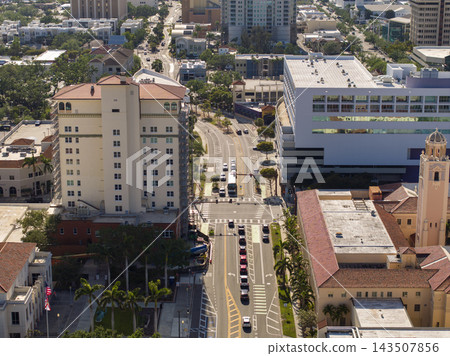 Lively Sarasota street scene shows pedestrians stepping onto the crosswalk while automobiles line up at the stop signal, emphasizing city infrastructure and traffic rules. 143507856