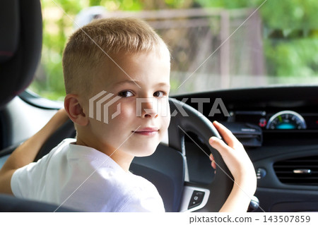 Little child boy behind the steering wheel of a car 143507859