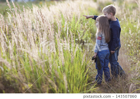Little boy and little girl standing holding hands looking on horizont. Rear view. Little boy and little girl standing holding hands looking on horizont. Rear view. 143507860
