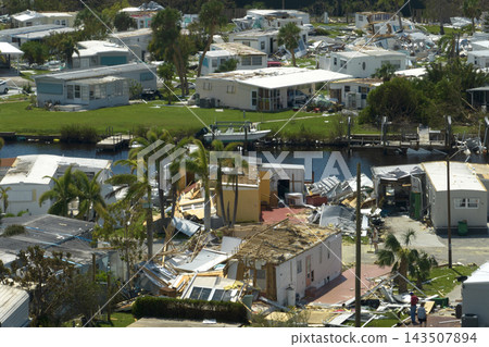 Hurricane strong wind destroyed suburban house roofs in Florida mobile home residential area. Consequences of natural disaster 143507894