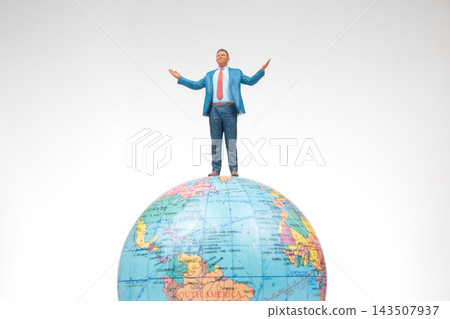 Miniature figures standing globe creating a sense of adventure and exploration in a simple setting Miniature figures standing globe creating a sense of adventure and exploration in a simple setting 143507937