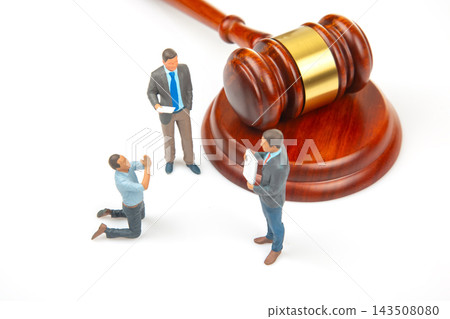Miniature figures engage in a scene representing a legal discussion by a gavel on a white surface 143508080