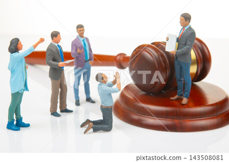 Miniature people interact with a gavel and a figure holding legal documents in a courtroom scene Miniature people interact with a gavel and a figure holding legal documents in a courtroom scene 143508081