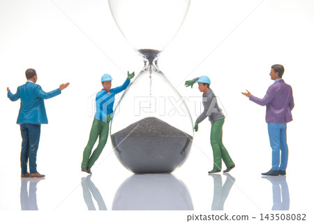 Miniature people working together to move sand in an hourglass Miniature people working together to move sand in an hourglass 143508082