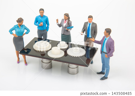 Miniature people discussing gears around a table in a meeting room Miniature people discussing gears around a table in a meeting room 143508485