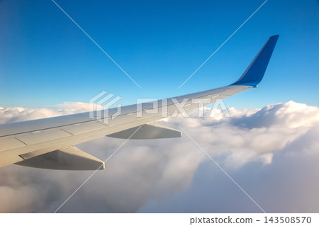 View of an airplane wing above white clouds during daytime View of an airplane wing above white clouds during daytime 143508570