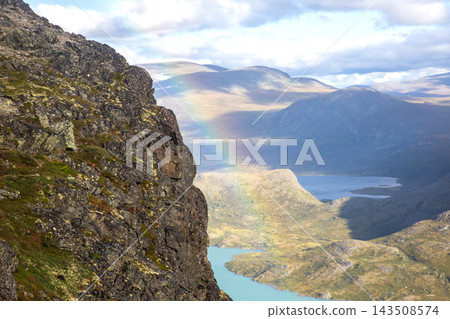 Colors in the sky appear above mountains and a lake in Norway during a sunny day Colors in the sky appear above mountains and a lake in Norway during a sunny day 143508574
