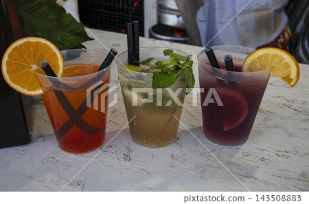 Three refreshing colorful summer cocktails in plastic cups with fruit garnishes Three refreshing colorful summer cocktails in plastic cups with fruit garnishes 143508883