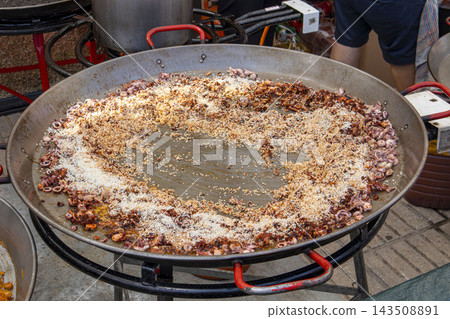 Preparing Traditional Seafood Paella with Rice and Squid in Large Pan Preparing Traditional Seafood Paella with Rice and Squid in Large Pan 143508891