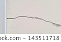 A long horizontal crack runs across the textured white plaster wall surface 143511718