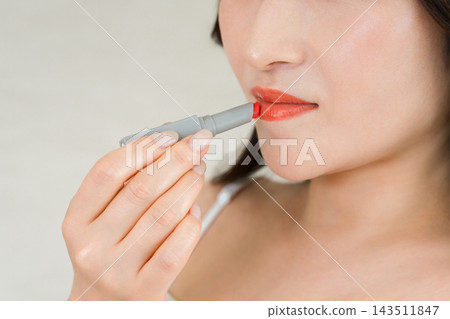 一位三十多歲的女性正在塗抹紅色唇膏的特寫。唇妝和美容/化妝品圖片，展現了美麗的嘴唇。 143511847