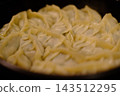 Homemade dumplings are packed tightly into a frying pan and being cooked. 143512295