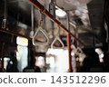A blurred-out image of the interior of a route bus with handrails spaced evenly apart. 143512296