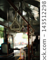 The blurred scenery outside the window and the handrails hanging alongside the route bus. 143512298