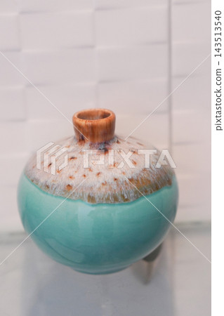 front view antique green and brown ceramic vase, on a glass shelf, white ceramic wall background, object, decor, fashion, copy space front view antique green and brown ceramic vase, on a glass shelf, white ceramic wall background, object, decor, fashion, copy space 143513540