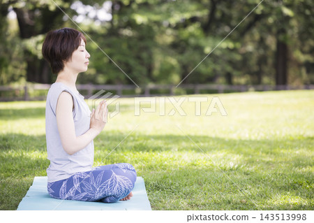 戶外瑜珈圖片:一位女子盤腿而坐,雙手合十祈禱。 戶外瑜珈圖片:一位女子盤腿而坐,雙手合十祈禱。 143513998