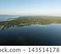 Aerial view of a lush green coastline bordered by calm blue water with small boats docked along the shore in Panglao, Bohol, Philippines 143514178