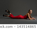 Woman in a red dress lies with her feet raised in black heels 143514865