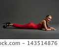 Woman in a red dress lies prone on a gray studio floor 143514876