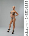 Woman in geometric mesh lingerie and heels standing in studio 143514885
