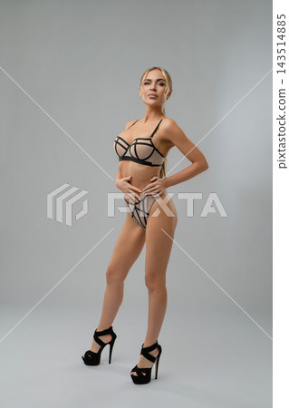 Woman in geometric mesh lingerie and heels standing in studio Woman in geometric mesh lingerie and heels standing in studio 143514885