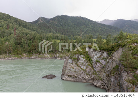 Mountain river flowing past steep rocky cliffs and green pine forests Mountain river flowing past steep rocky cliffs and green pine forests 143515404